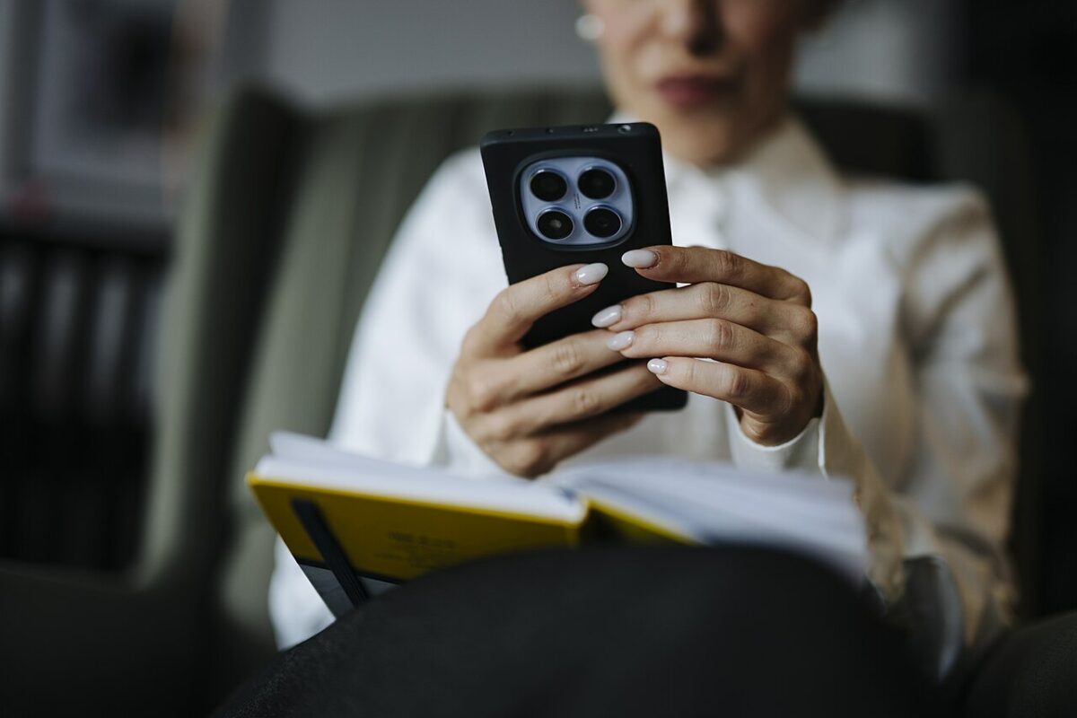 Une personne tient un smartphone au-dessus d’un livre ouvert
